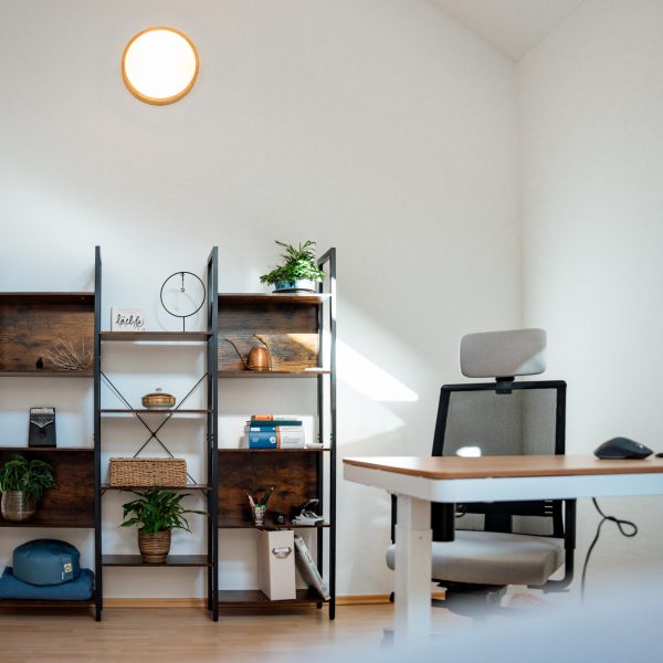 Innenaufnahme des Therapieraums mit Schreibtisch und Bücherregal.